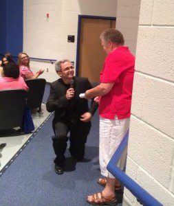 Supt. Eric Williams on his knees presenting his poem to Mary, bus driver of 37 yrs.