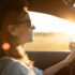 Happy female driving her car at sunset, feeling free.